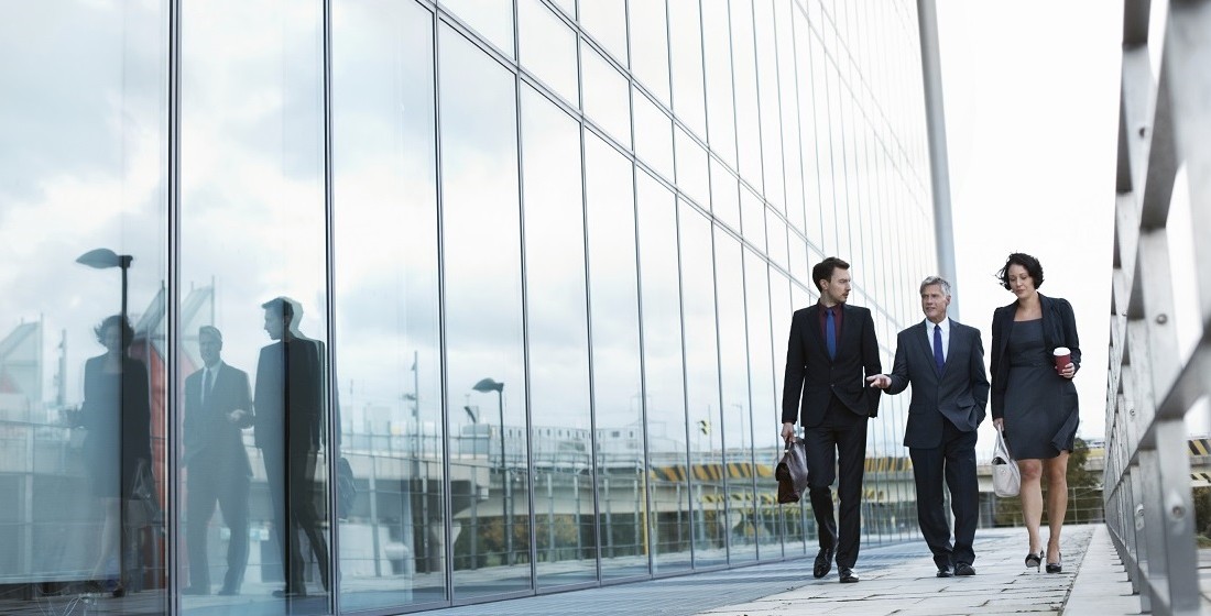 professionals walking alongside glass building