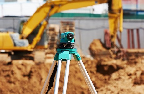 Surveying tool in front of construction site representing civil engineering contractors