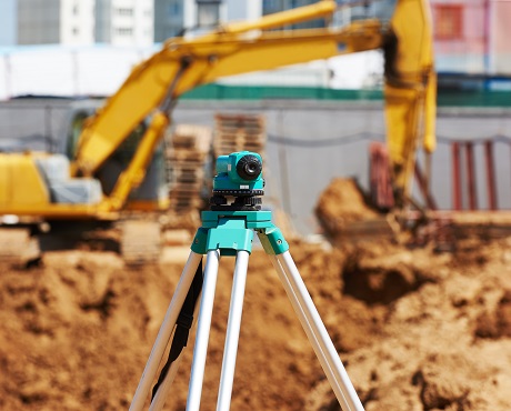 Surveying tool in front of construction site representing civil engineering contractors