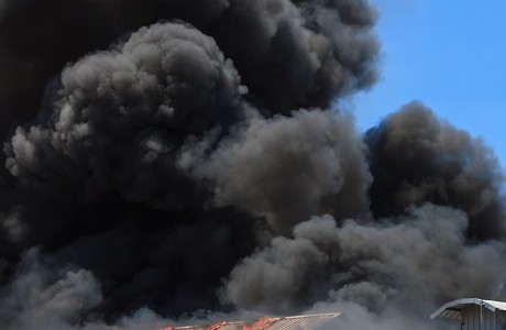 black smoke rising above a burning building representing Loss Assessors Fee Indemnity Insurance