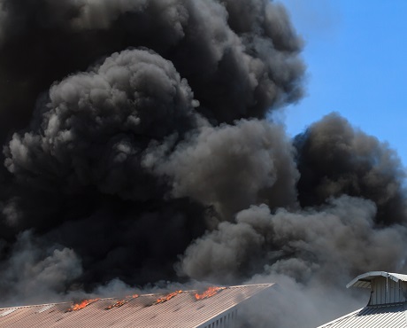 black smoke rising above a burning building representing Loss Assessors Fee Indemnity Insurance